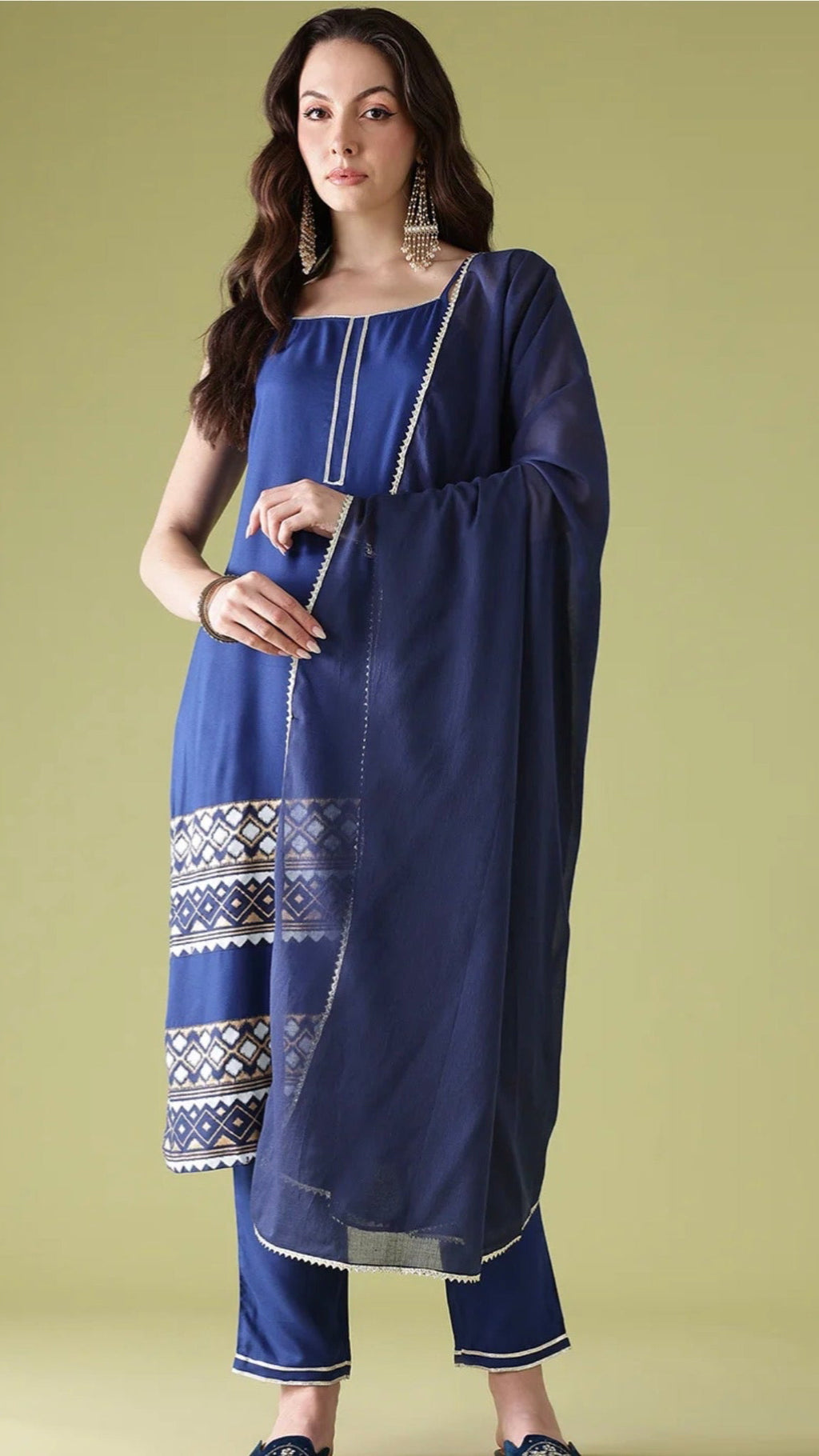 Woman wearing a blue traditional outfit with intricate patterns on a green background