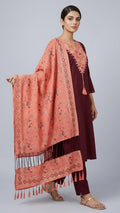 Woman holding a pink patterned shawl against a gray background