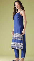 Woman wearing a blue dress with a patterned hem on a green background