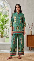 Woman wearing a patterned outfit standing in a room with a window and furniture.