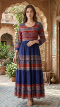 Woman wearing a blue and red patterned dress standing in an ornate architectural setting.
