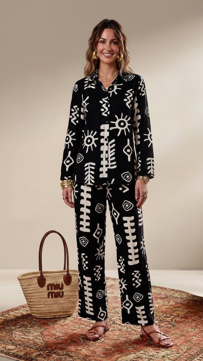 Woman wearing a black and white patterned outfit with a woven bag on a beige background