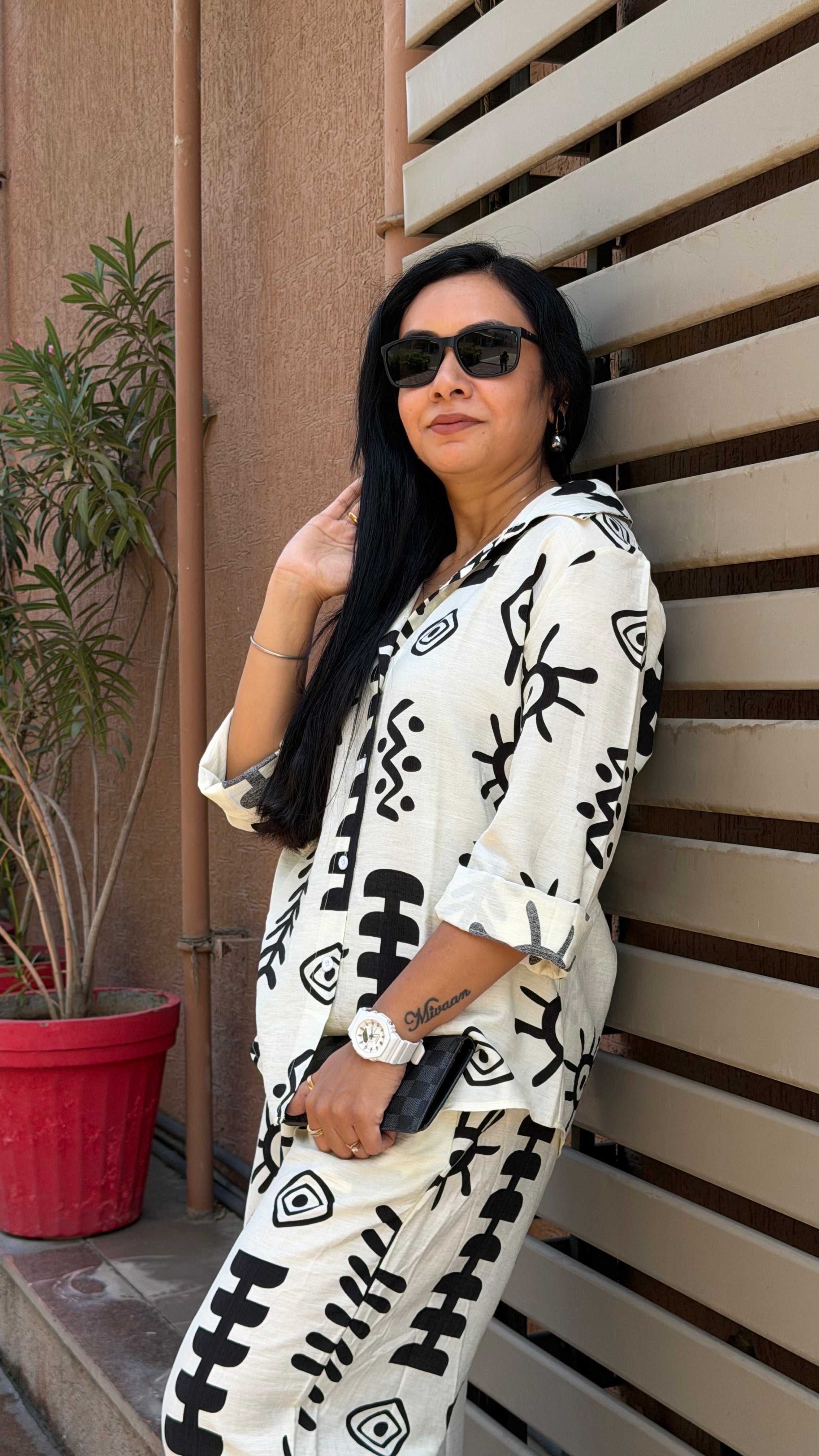 Woman wearing a white outfit with black patterns against a wooden background