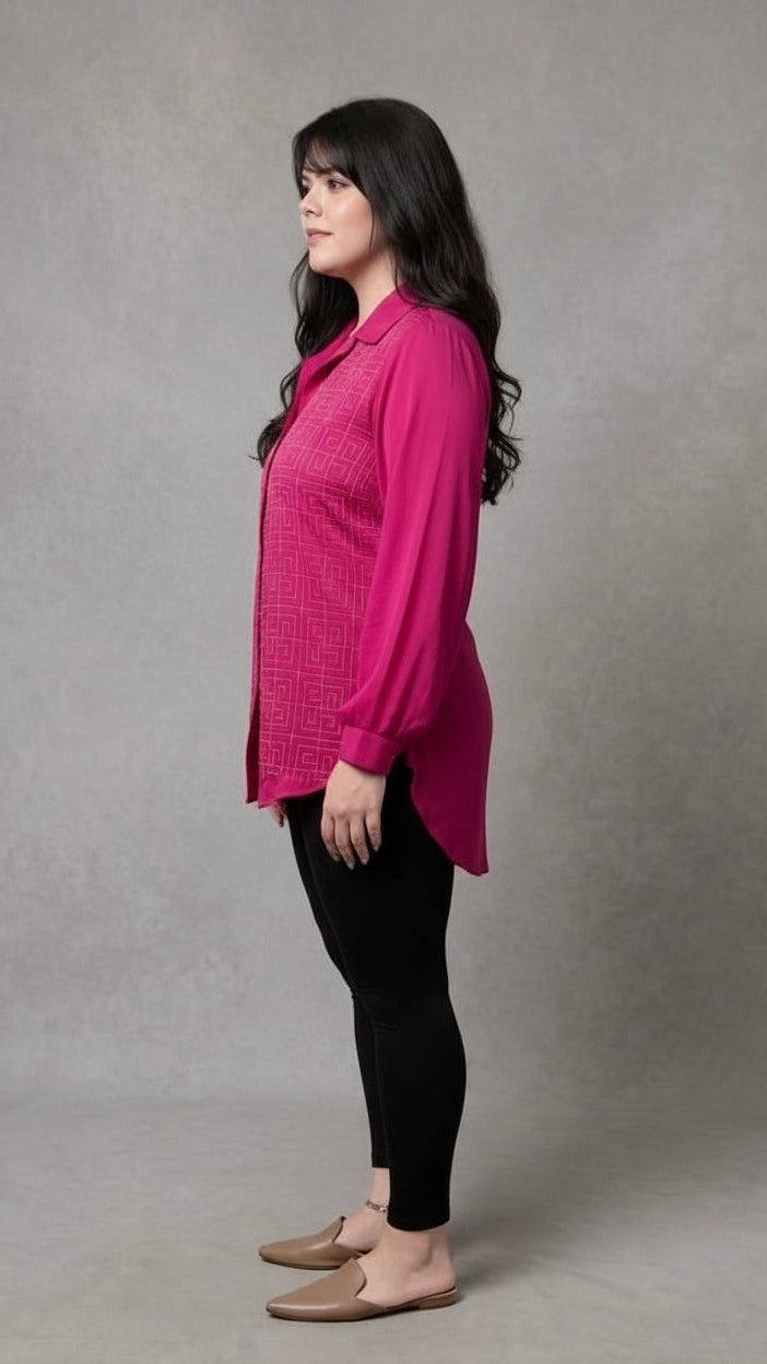 Woman wearing a bright pink blouse and black pants against a gray background