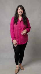 Woman wearing a bright pink shirt and black pants against a gray background