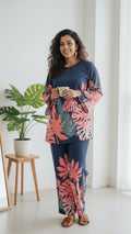 Woman in a floral dress standing in a room with a mirror and plant.