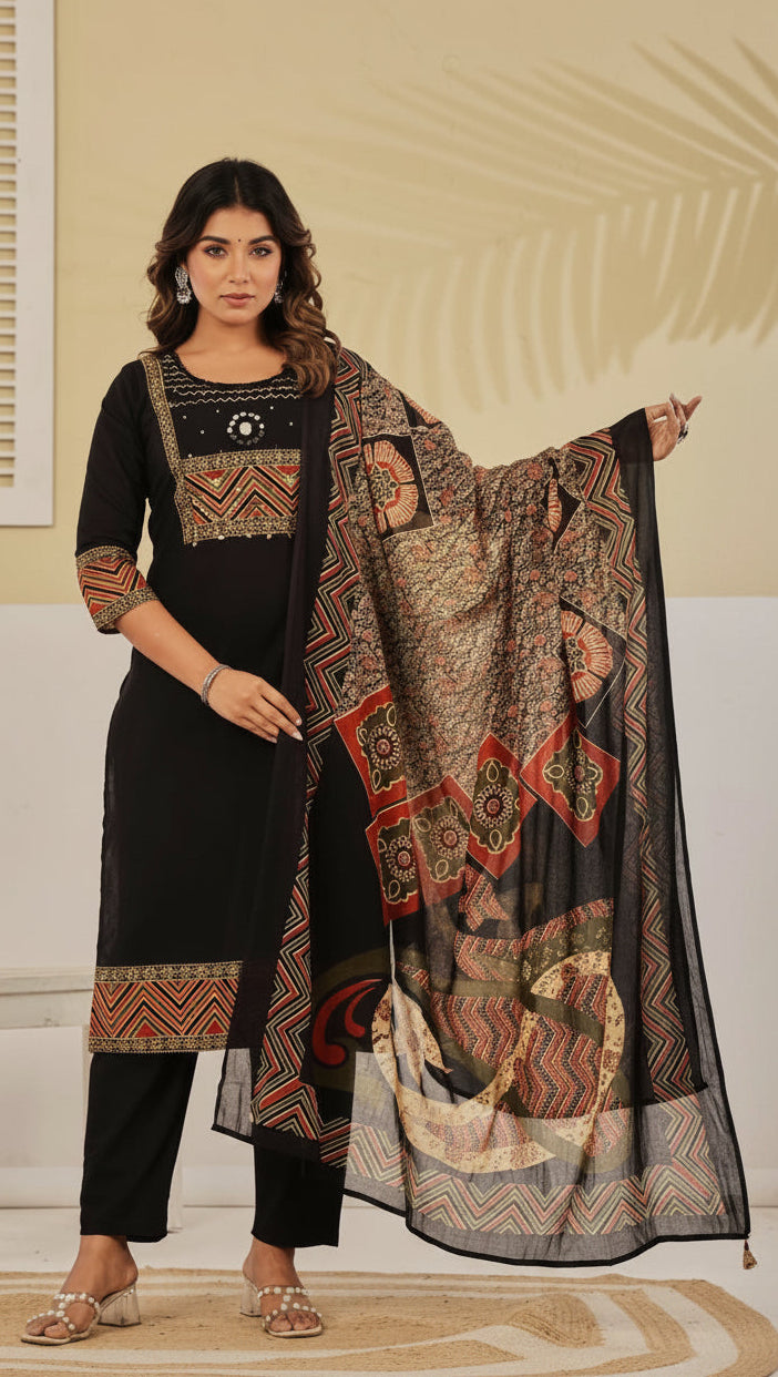 Woman wearing a traditional outfit with a black top and pants, holding a patterned dupatta.