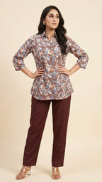 Woman wearing a floral blouse and maroon pants on a beige background